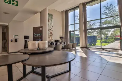 a living room with tables and chairs and windows at Menlyn Maine 1413 in Pretoria