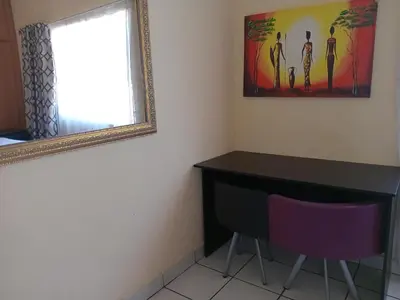 a room with a desk and a mirror and a window at Yana House in Polokwane