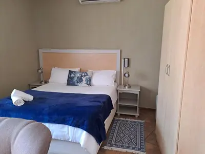 a bedroom with a large bed with a blue blanket at Amigos Bed & Breakfast - No loadshedding in Nelspruit