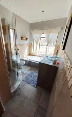 a bathroom with a shower and a tub and a toilet at Oryx Lodge in Brits