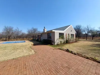 a white house with a brick driveway at Oryx Lodge in Brits