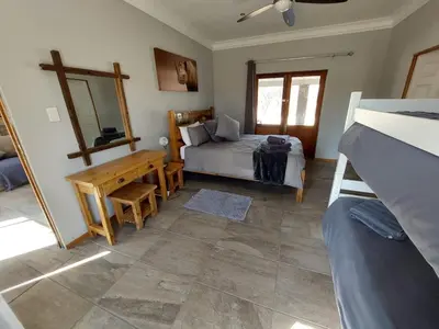 a bedroom with a bed and a table and a mirror at Oryx Lodge in Brits