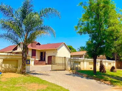 a house with a gate and two palm trees at Inconova fly in Kempton Park