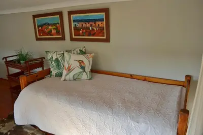 a bedroom with a bed with two paintings on the wall at Kudusdrift Farmstay in Vaalwater