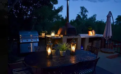 a table with lights on a patio with a stove at Kudusdrift Farmstay in Vaalwater