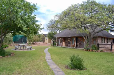 a house with a grassy yard with a table and a bench at Kudusdrift Farmstay in Vaalwater