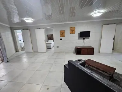 a large room with a couch and a tv on a wall at Sally's Place in Boksburg