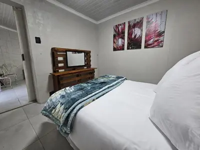a bedroom with a bed and a tv on a dresser at Sally's Place in Boksburg
