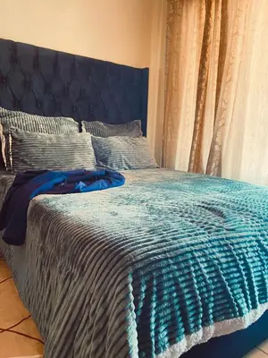 a bed with a blue blanket and pillows on it at Inocova Fly in Kempton Park