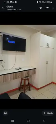 a kitchen with white cabinets and a tv on the wall at Limelight in Polokwane
