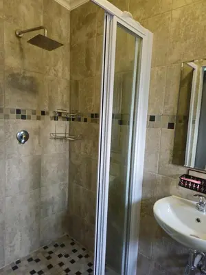 a bathroom with a shower and a sink at The Cypress Guesthouse in Pretoria