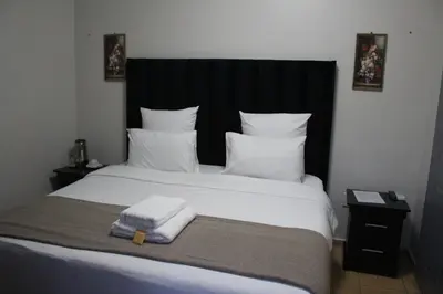 a bedroom with a large white bed with a black headboard at The Cypress Guesthouse in Pretoria