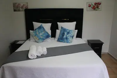 a bedroom with a large white bed with two towels at The Cypress Guesthouse in Pretoria