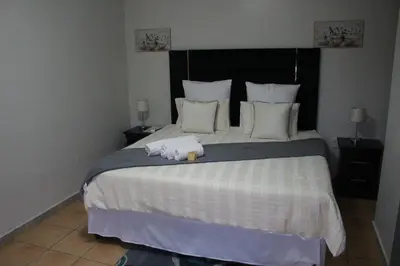 a bedroom with a large bed with a stuffed animal on it at The Cypress Guesthouse in Pretoria