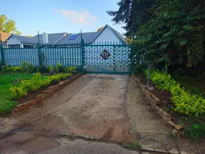 a blue fence with a gate in a garden at The Cypress Guesthouse in Pretoria