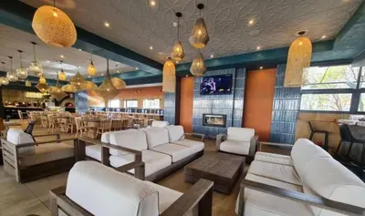 a restaurant with white couches and a bar at The Blyde Apartment in Pretoria