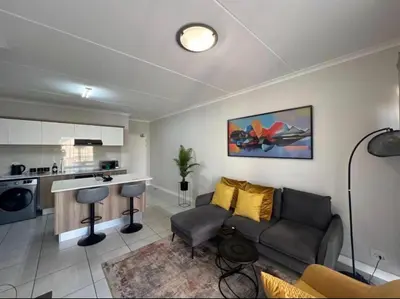 a living room with a couch and a kitchen at The Blyde Apartment in Pretoria