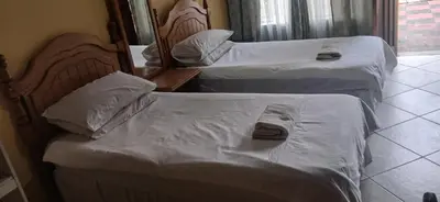 two beds in a hotel room with towels on them at 16 Besembos contractors accommodation in Witbank