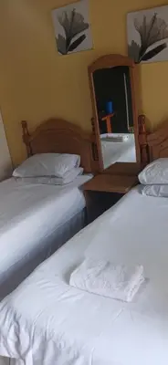 two beds in a hotel room with a mirror at 16 Besembos contractors accommodation in Witbank