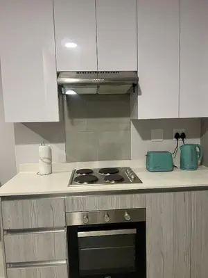 a kitchen with a stove top oven and white cabinets at Modern Apartment in Centurion in Centurion