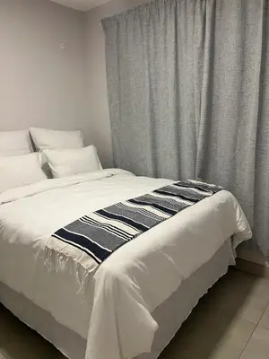 a white bed with a black and white blanket on it at Modern Apartment in Centurion in Centurion