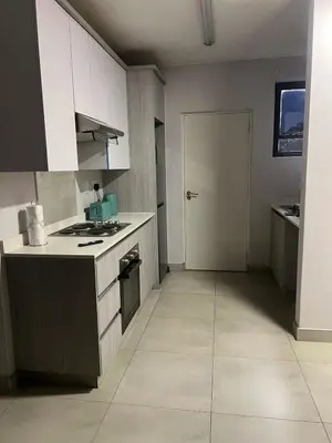a kitchen with white cabinets and a stove top oven at Modern Apartment in Centurion in Centurion