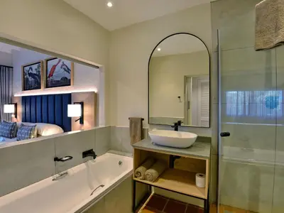 a bathroom with a sink and a tub and a mirror at ANEW Resort Hazyview Kruger Park in Hazyview