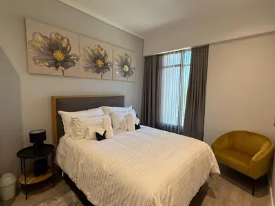 a bedroom with a white bed and a chair at 136 Trilogy in Pretoria
