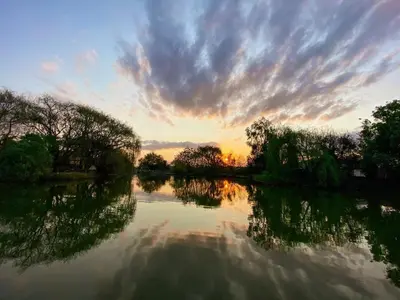 a sunset over a river with trees and clouds at The Nugget Guest Lodge in Kempton Park