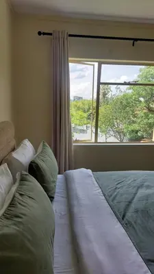 a bed in a bedroom with a large window at La Boheme in Pretoria