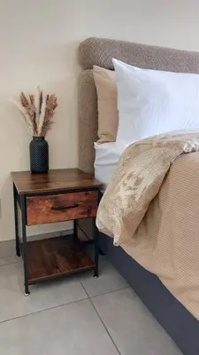 a bed with a wooden nightstand next to a table with a bed sidx sidx at La Boheme in Pretoria
