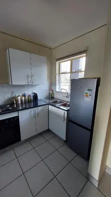 a small kitchen with a refrigerator and a sink at La Boheme in Pretoria