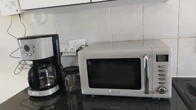 a microwave sitting on a counter next to a coffee maker at La Boheme in Pretoria