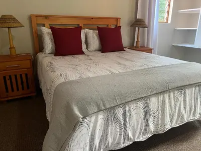 a bedroom with a large bed with red pillows at B&B on the Sabie in Sabie