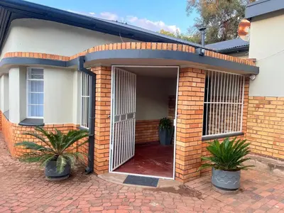 a brick house with an open door with two plants at 326onMackenzieSt in Pretoria