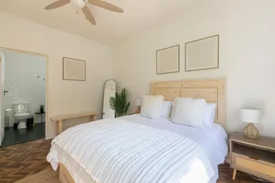 a white bedroom with a bed and a ceiling fan at Maroelana Home in Pretoria