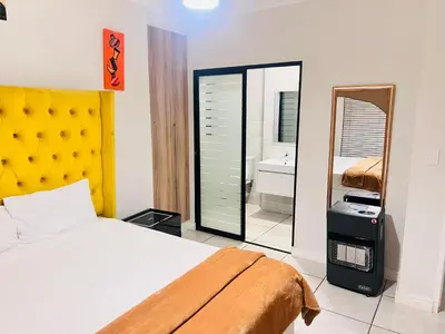 a bedroom with a bed with a yellow headboard and a mirror at The Blyde Crystal Lagoon in Pretoria