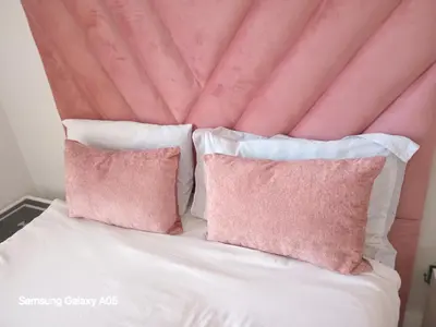 a bed with white sheets and pink pillows at The Blyde Crystal Lagoon in Pretoria