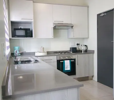 a kitchen with white cabinets and a stove top oven at PC Luxe Stays exquisite apartments in Erand