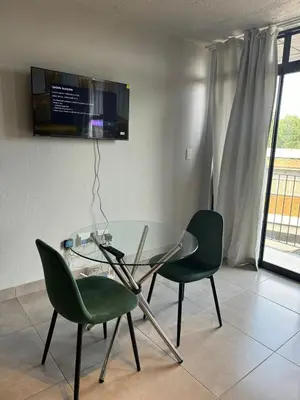 a dining room with a glass table and two green chairs at Circa apartment hotel in Pretoria