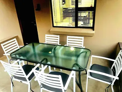 a glass table with white chairs and a window at Moonlight in Marloth Park
