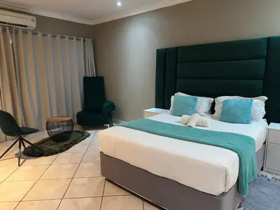 a bedroom with a large bed and a chair at BY Guest House in Hartbeespoort
