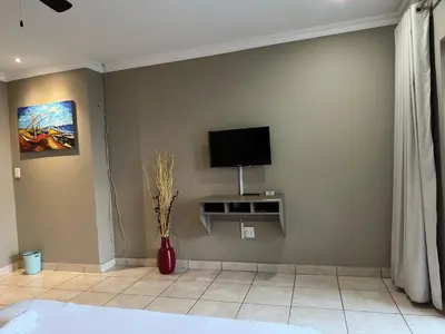 a living room with a tv on the wall at BY Guest House in Hartbeespoort