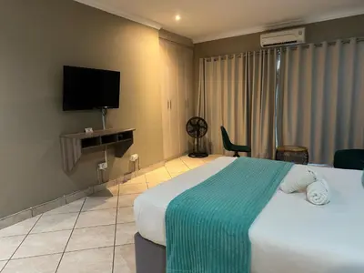 a hotel room with a bed and a flat screen tv at BY Guest House in Hartbeespoort