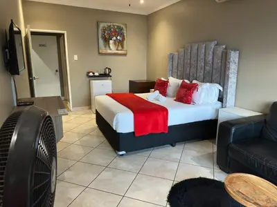 a hotel room with a bed and a couch at BY Guest House in Hartbeespoort