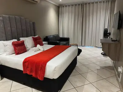 a bedroom with a large bed with a red blanket at BY Guest House in Hartbeespoort