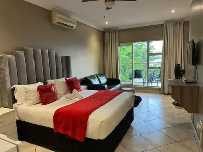 a bedroom with a large bed with a red blanket at BY Guest House in Hartbeespoort