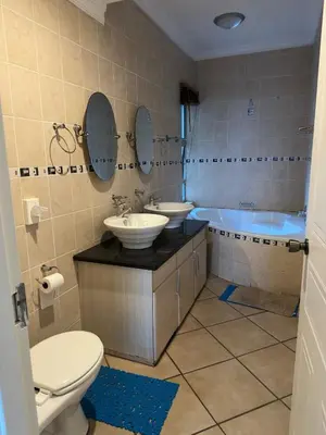 a bathroom with a toilet and two sinks and a tub at BY Guest House in Hartbeespoort