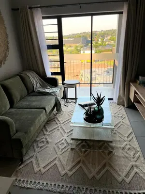 a living room with a couch and a glass table at The Aura at Castle Gate in Pretoria
