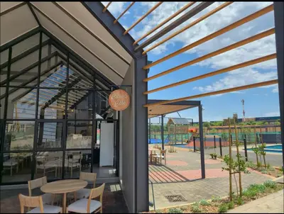a building with a table and chairs and a patio at The Aura at Castle Gate in Pretoria